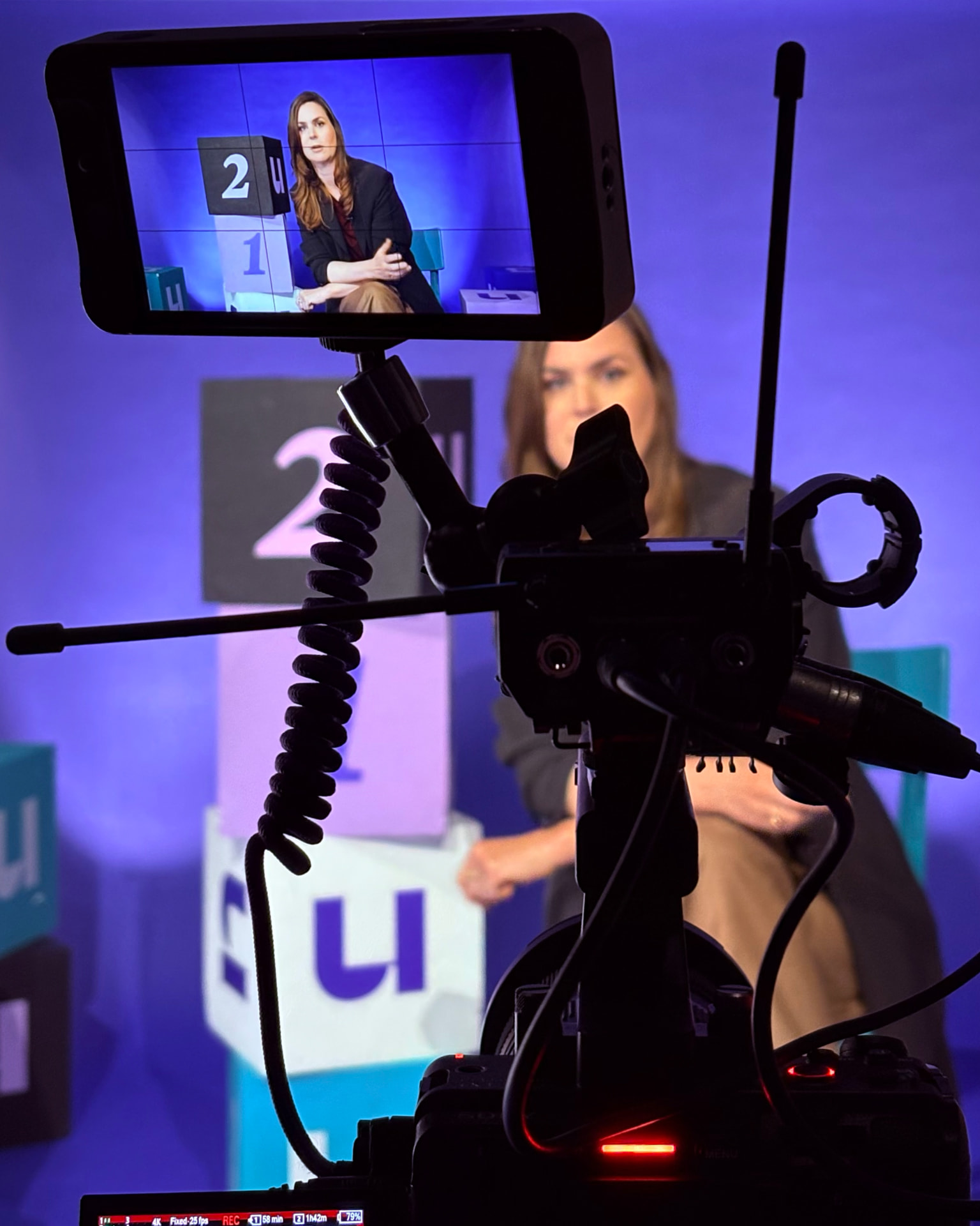 Camera met monitor tijdens een opname in de studio van U Studio: presentator in beeld, decorkubussen op de achtergrond
