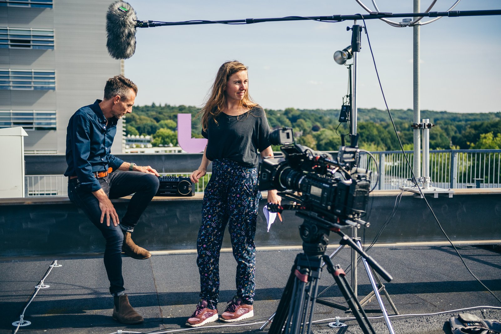 De redactie van U Studio aan het werk op een dakopname, met camera en geluidsapparatuur op de voorgrond